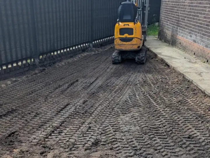 Mini digger excavating and preparing the ground before a new driveway is laid