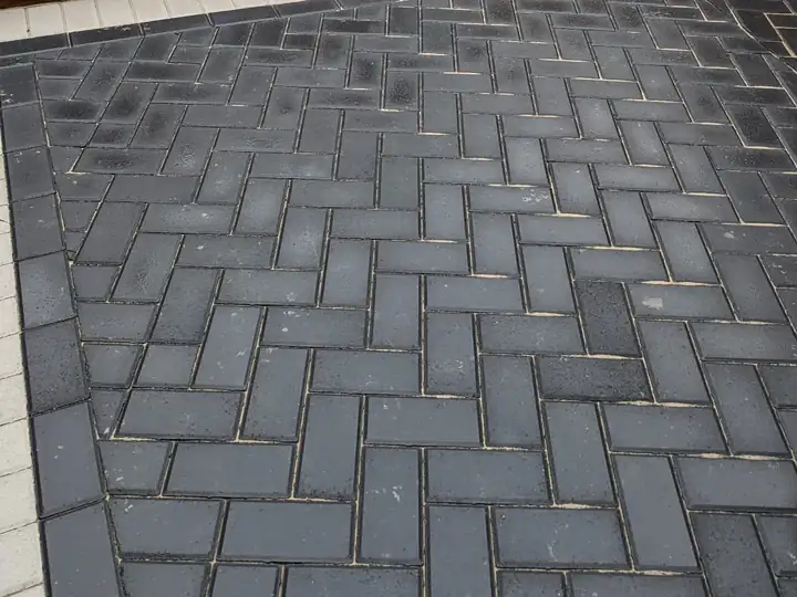 Charcoal herringbone block paving driveway with a light border and sleeper edge